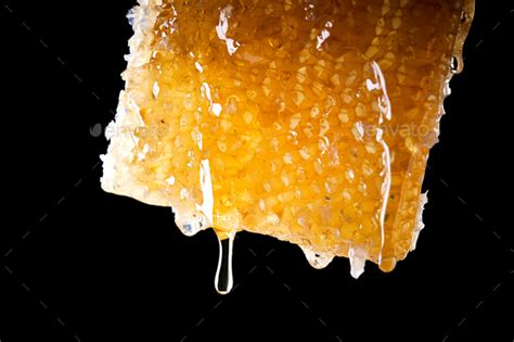 Close Up Of Honey Dripping From Honeycomb Against Black Background