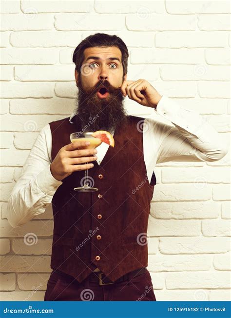 handsome bearded man with long beard and mustache has stylish hair on surprised face holding