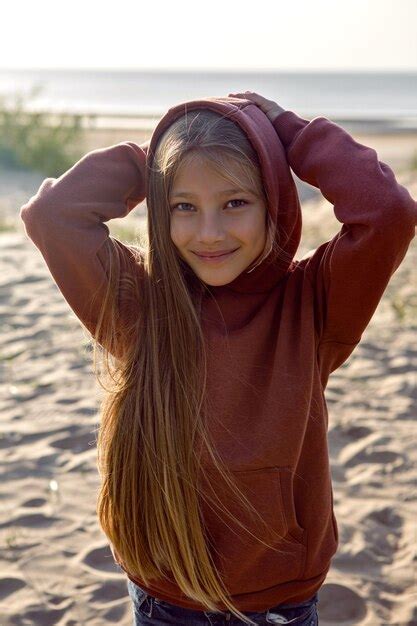 Premium Photo Portrait Of A Girl With Long Hair Standing On A Sandy Beach In A Hoodie And Hood