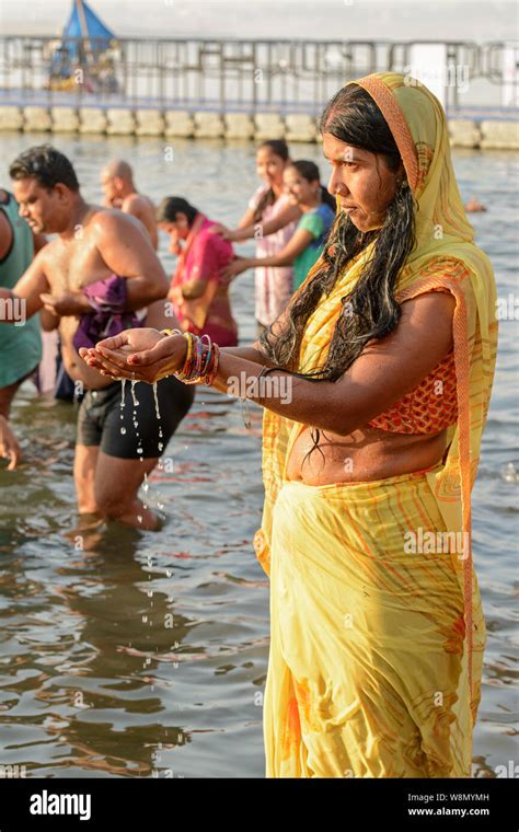 A Young Indian Hindu Woman Wearing A Sari Performs An Early Morning Bathing Ritual In The River