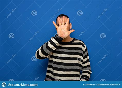 Man With Big Hands Dressed In A Striped Sweater Hiding His Face Behind
