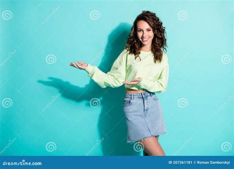 Photo Portrait Of Curly Pretty Brunette Keeping Hands Forward Showing At Empty Space Smiling