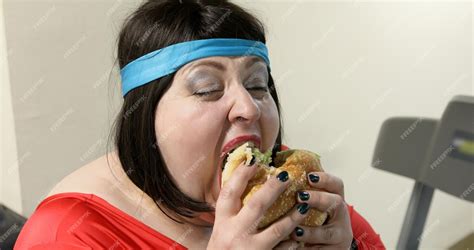 Premium Photo Hungry Overweight Woman Eats A Big Burger In The Gym The Fat Woman Laughs