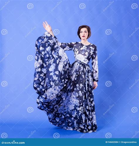 Femme Magnifique Avec La Longue Robe De Vol Sur Le Fond Bleu Photo