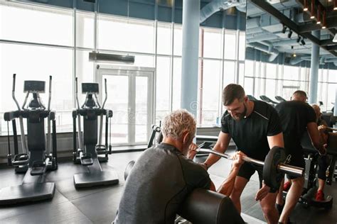 Young Trainer Supports Senior Client At Gym Stock Image Image Of Arms