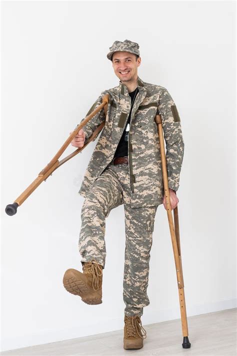 Portrait Of Soldier With Crutches Against White Background Stock Image