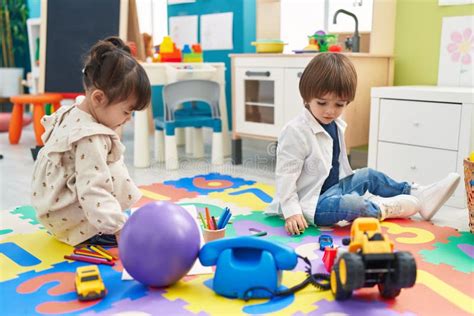 Two Kids Playing With Toys Sitting On Floor At Kindergarten Stock Image