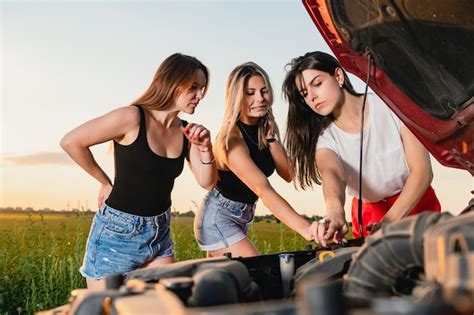 Tres hermosas mujeres atrapadas durante un viaje por carretera intentan arreglar el vehículo
