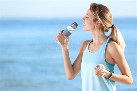 Young Woman Drinking Water From Bottle After Fitness Exercises On Beach
