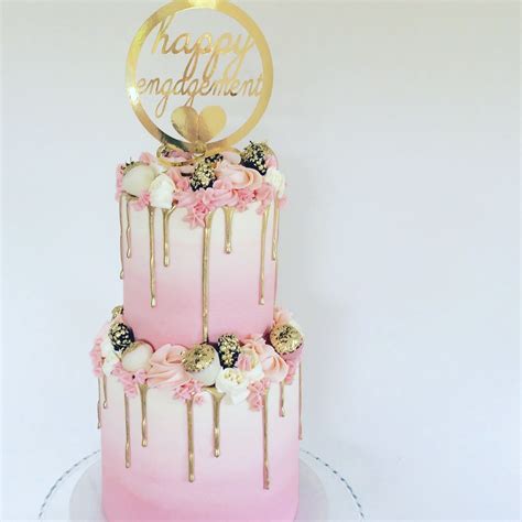 two tier pink and gold cake with gilded fruits and a gold drip billies first birthday