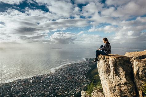 Woman Sitting On The Edge Of A Cliff Overlooking Cape Town At Sunset By Micky Wiswedel Hiking