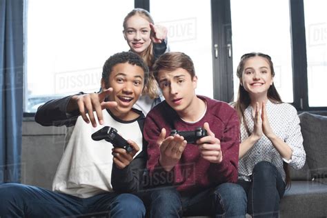 Happy Multicultural Teenagers Playing Video Games With Joysticks At