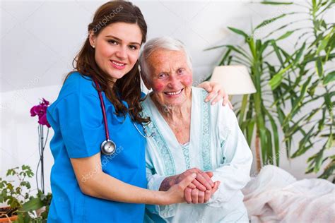 Glückliche Seniorin liegt mit einer fürsorglichen Krankenschwester ...
