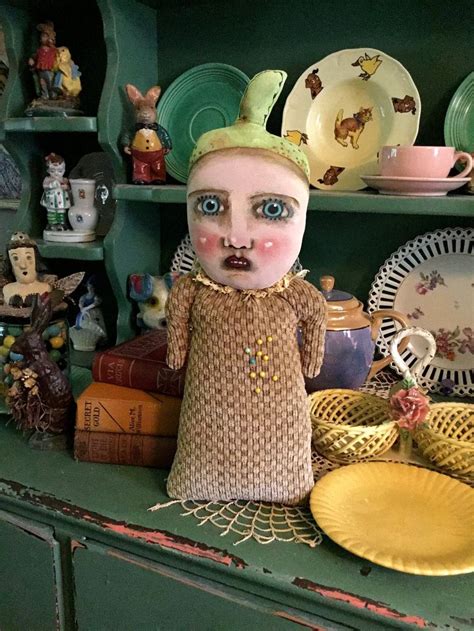 A Doll Is Sitting On Top Of A Green Cabinet With Many Plates And Dishes