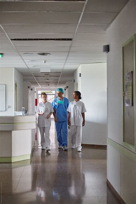 Hospital Staff Walking And Talking In A Hallway By Stocksy