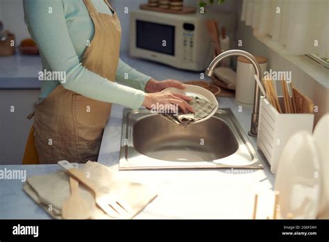Cropped Image Of Attractive Young Woman Is Washing Dishes While Doing
