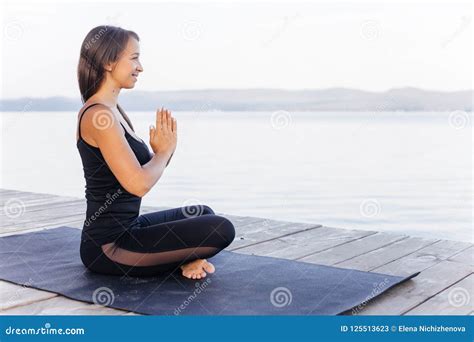 Young Attractive Smiling Woman Practicing Yoga On A Lake Stock Image