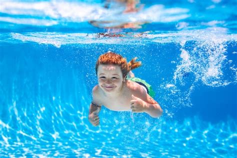 Маленький ребенок девочка плавающая под водой в детском бассейне