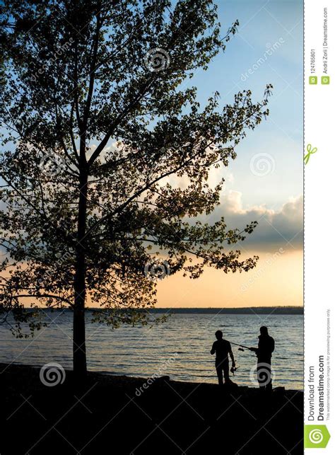 Silhouettes Of Two People And A Tree On The River Bank Sunset Stock