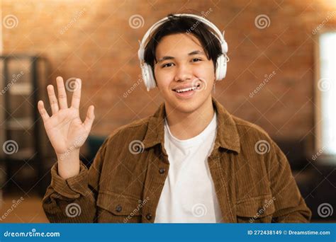 Cheerful Japanese Student Guy Posing Wearing Headphones Waving Hand