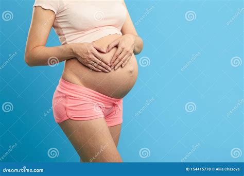 Pregnant Girl Putting Her Palms In The Heart Shape On Her Belly Foto De