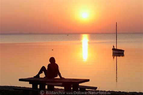 Romantik Stimmung Am See Frau Bei Sonnenuntergang Auf Tisch Sitzen Boot In Roter Sonne Bild