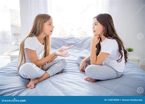 Profile Side Photo Of Astonished Girls Sit Bed Legs Crossed Have