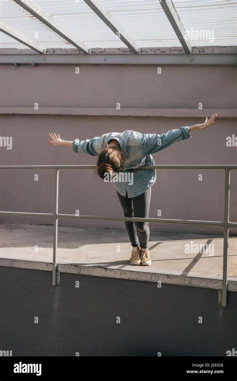 Young Woman Bending Over Railing With Arms Outstretched Stock Photo Alamy
