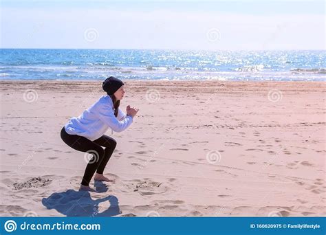 Woman Makes Squats On Sea Sand Beach Fitness Outdoor Sport Exercises Training Stock Image