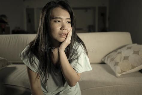 Young Beautiful Sad And Depressed Asian Japanese Woman At Home Sofa
