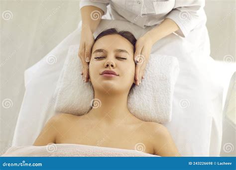 Calm Beautiful Woman Enjoys Relaxing Facial Massage Given To Her By Specialist In Spa Stock