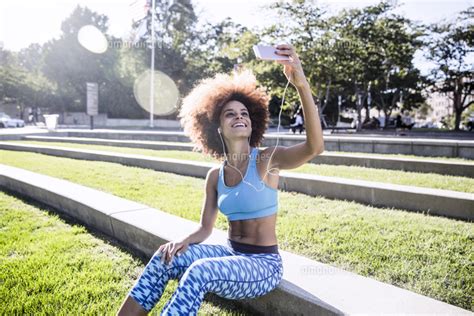 Happy Woman Taking Selfie While Sitting In Park