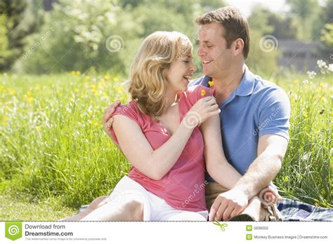 pares que sentam se ao ar livre prendendo o sorriso da flor foto de stock imagem de afetuoso