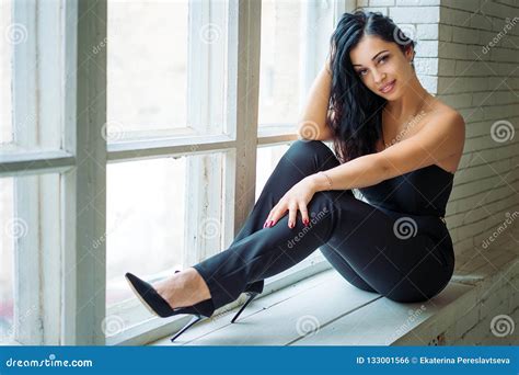 Portrait Of A Beautiful Young Woman Sitting On The Windowsill Stock