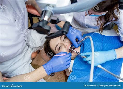 Dentist Looking Through A Microscope At The Patientand X27s Teeth