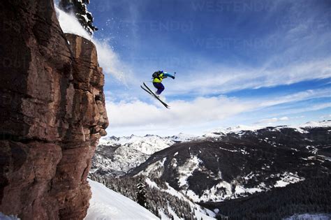 A Athletic Skier Jumping Off A Cliff In The Backcountry On A Sunny