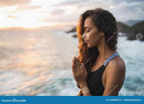 Woman Praying And Meditating At Sunset With Beautiful Ocean And