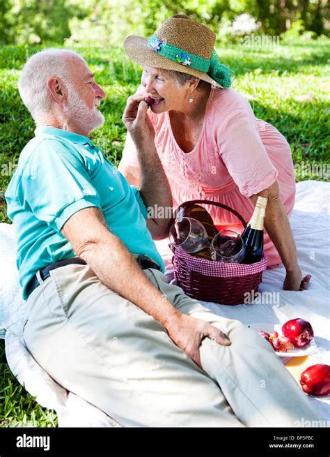 Romantic Senior Couple On A Picnic Hes Feeding Her Grapes Stock Photo