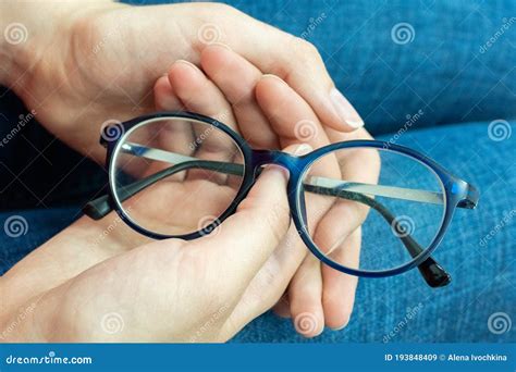 Close Up Of Human Hands Holding Blue Rimmed Glasses On Their Knees Eyes Rest From Glasses Eye