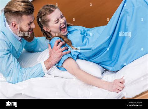 Pregnant Woman Giving Birth In Hospital While Man Hugging Her Stock