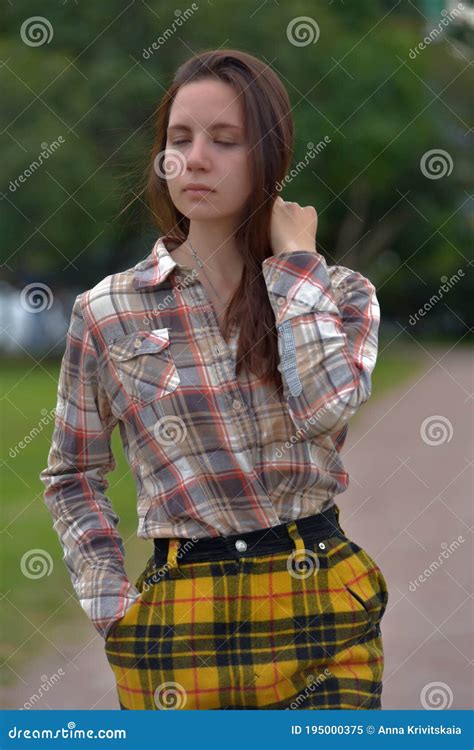 Slender Brunette Girl In A Plaid Skirt In The Summer In The Park Stock