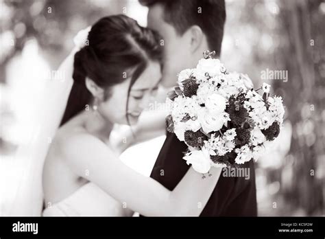 Young Asian Newly Wed Couple Hugging Each Other During Wedding Ceremony Focus On The Bouquet