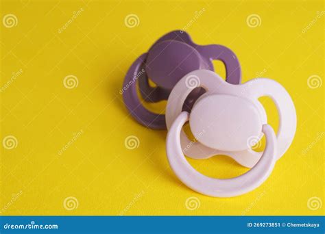 New Baby Pacifiers On Yellow Background Space For Text Stock Image