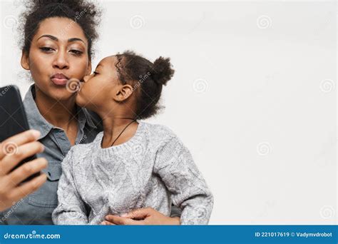 African Mother And Daughter Kissing While Using Cellphone Stock Image