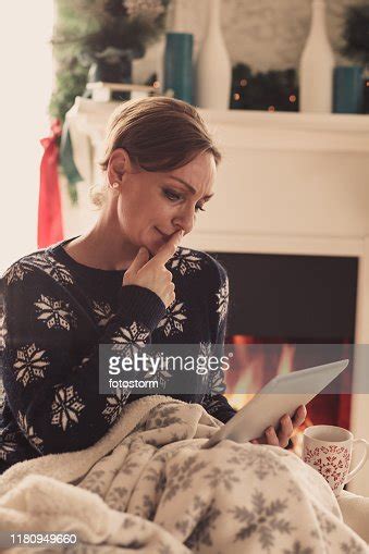 Portrait Of A Woman Pondering Over A Digital Tablet High Res Stock