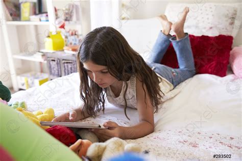 Junges Mädchen liegen auf dem Bett mit digitalen Tablet Foto vorrätig Crushpixel