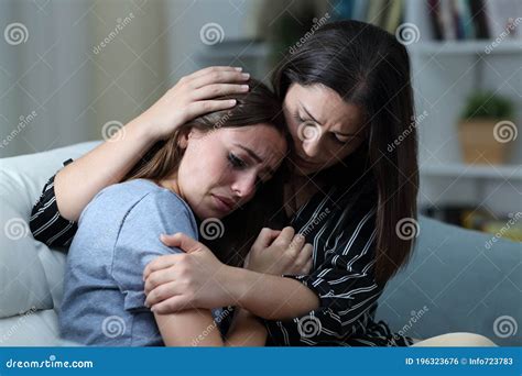 Sad Teen Crying Being Comforted By Her Sister At Home Stock Photo