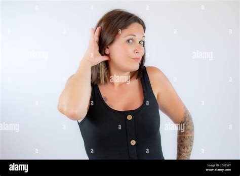 Beautiful Young Woman In Black Shirt Making Listening Gesture Stock