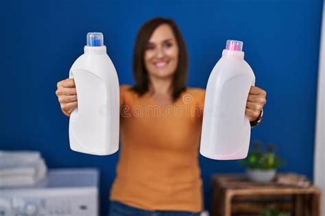 Middle Age Woman Smiling Confident Holding Bottles Of Detergent At