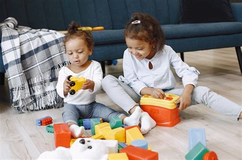 Premium Photo Two Pretty Kids Sit On Floor And Play With Toys Near